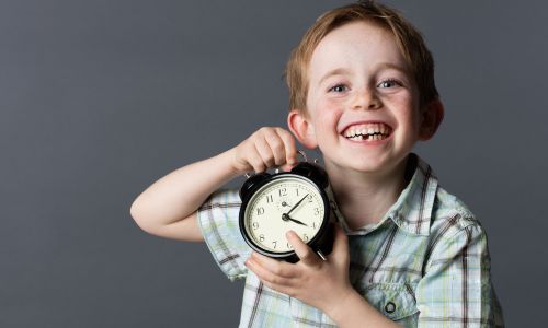 a young boy holding a clock