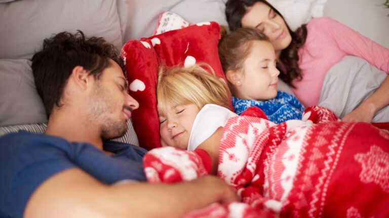 a family sleeping in holiday blankets depicting routine changes during holidays
