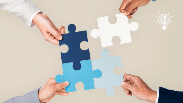 Four hands holding interlocking puzzle pieces in various shades of blue and white, symbolizing collaboration and problem-solving.