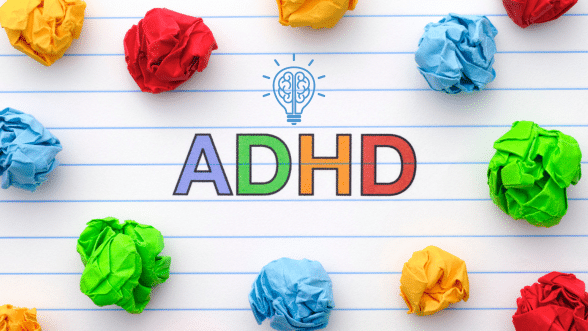 Colorful ADHD lettering on lined paper with a lightbulb brain icon, surrounded by crumpled papers, symbolizing creativity and the challenges of ADHD.