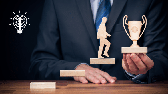 Wooden figure stepping up blocks towards a trophy, symbolizing goal achievement, workplace motivation, and success.