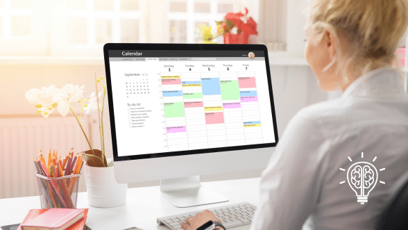 A person sitting at a desk using a digital calendar on a laptop, symbolizing productivity and digital organization tools.