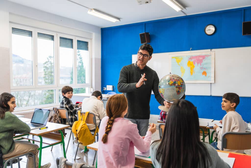 teacher explaining lesson using globe in classroom