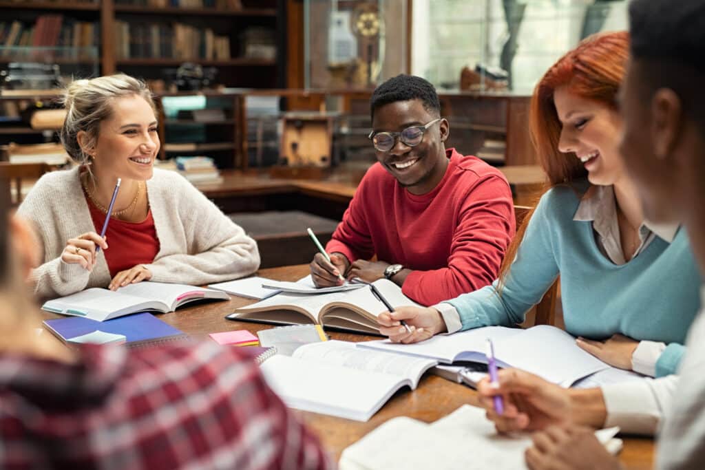 Happy college students studying together and laughing.