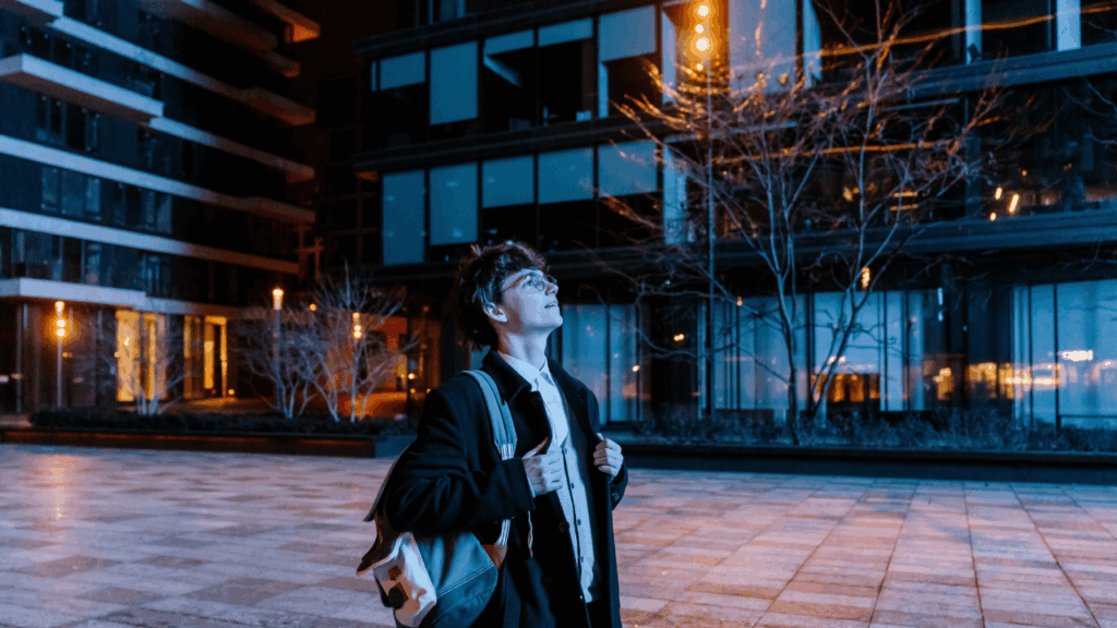 A male intern is standing and looking up on the street