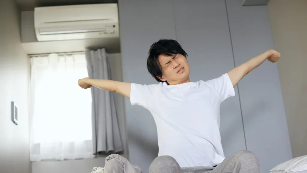 Young man stretching in bed, illustrating the importance of consistent wake-up times as the foundation of adhd routine building.