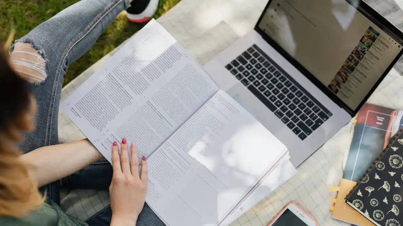 Overhead view of a college student studying outdoors with a laptop and textbooks, utilizing environment changes for effective adhd routine building.